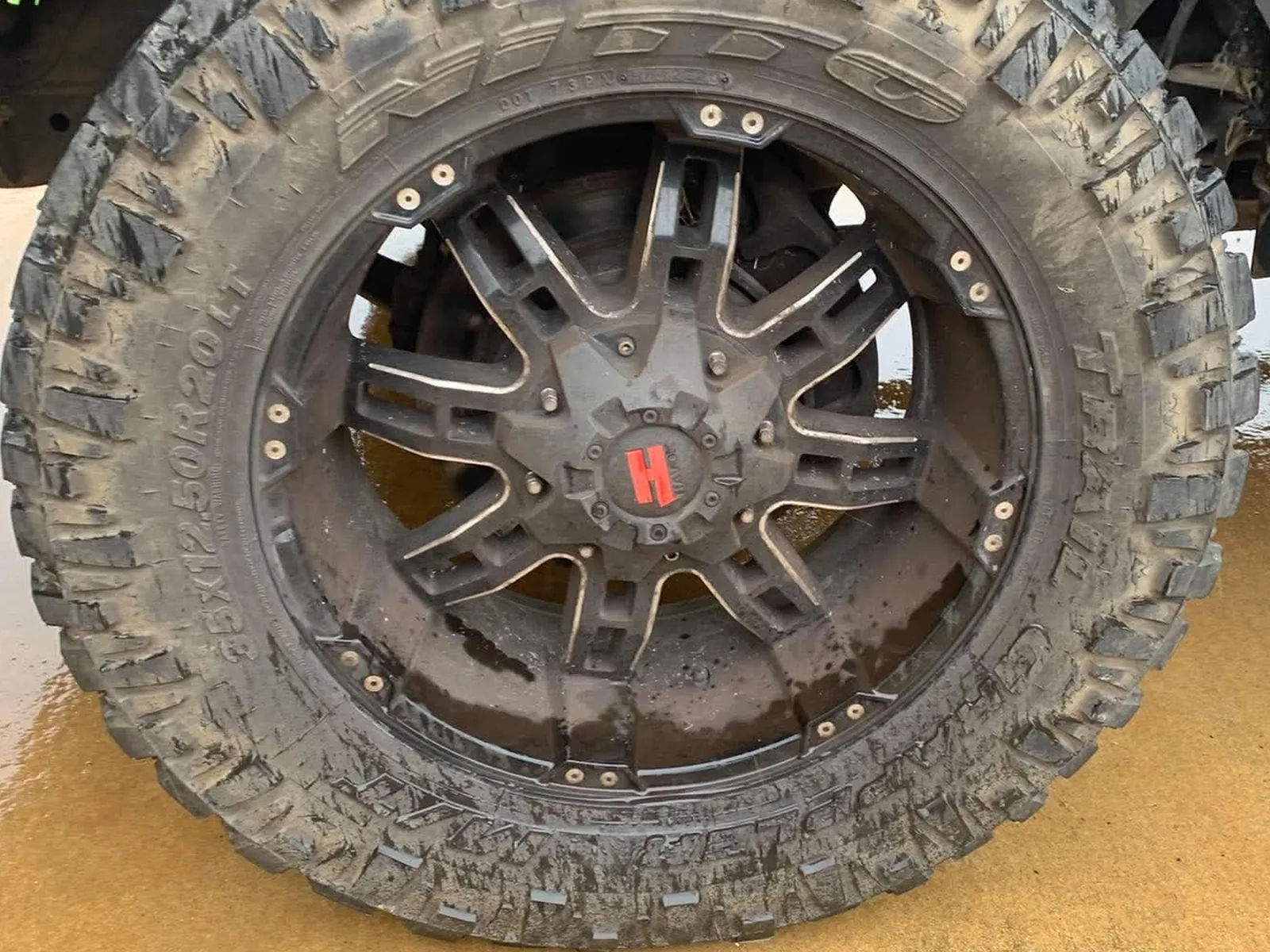 Truck wheel and mud-terrain tyre before detailing, coated in dust and brown road grime