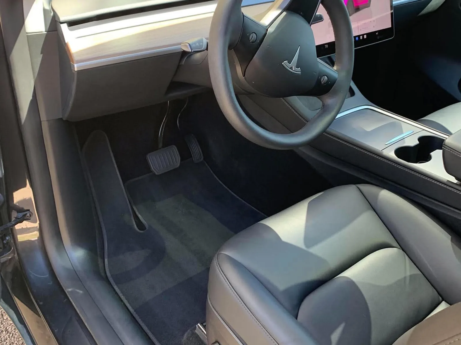 The same driver footwell after detailing, with clean vacuumed carpet and a wiped door sill