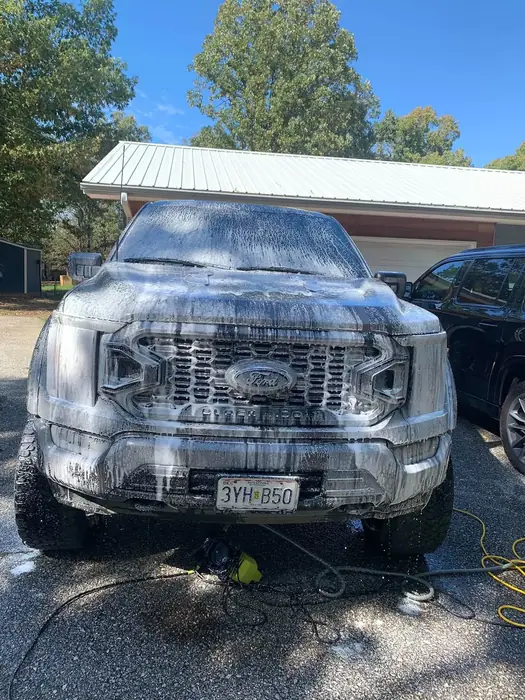 Ford F-150 front end covered in wash foam on a driveway