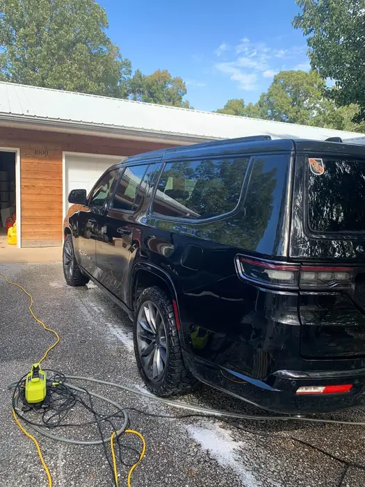 Large dark SUV being washed on a driveway