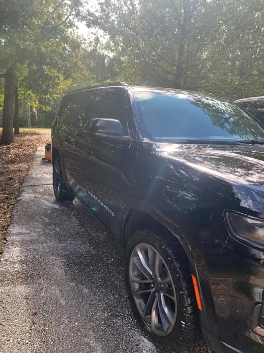 Dark Jeep Grand Cherokee rinsed clean on a wet driveway